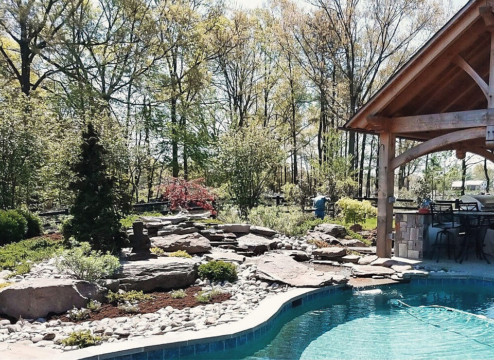 Stone falls running into a pool beside a timber pavilion