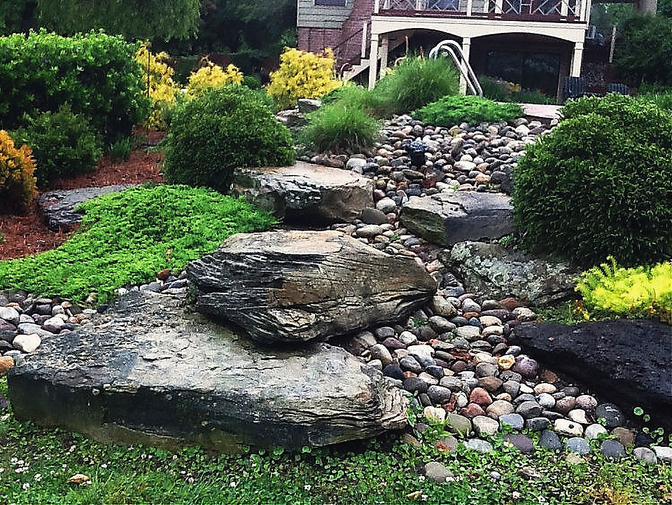 Boulders and river stone running down a slope below a deck