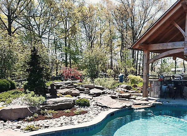 Stone falls into a pool, a timber pavilion beside it