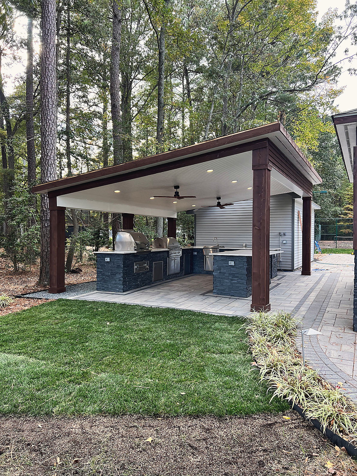 A covered outdoor kitchen, with new sod laid up to the pavers